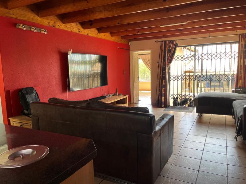 Spacious living area featuring exposed timber ceiling beams, tiled flooring, and direct access to the outdoor area through a secure sliding door.