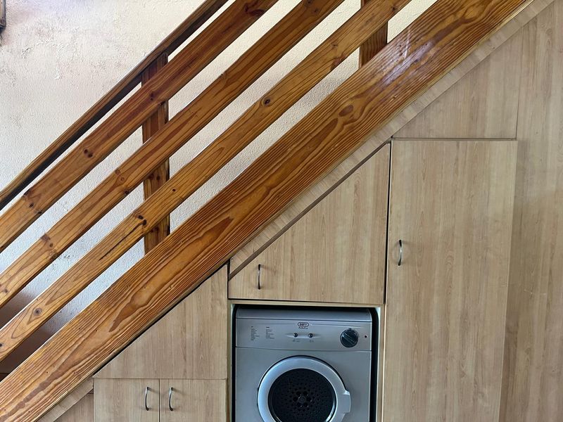 Efficient under-stair laundry area featuring custom built-in cabinetry and integrated appliance space.