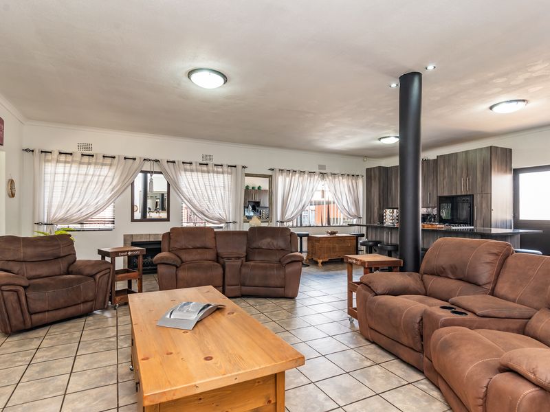 Spacious open-plan living area featuring tiled floors, a central structural column, a fireplace, and a modern kitchen with integrated cabinetry and island.