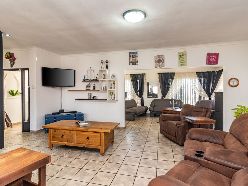 Spacious living area featuring tiled flooring, a central support column, and an open-plan layout connecting to an adjacent lounge space.
