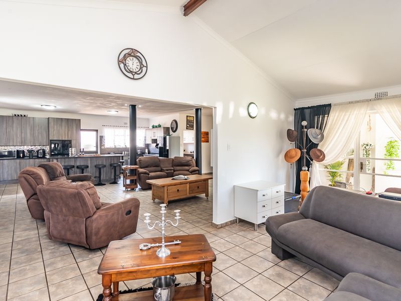 Spacious open-plan living area featuring tiled floors, vaulted ceilings, and a connected kitchen with island, providing a functional and airy layout.