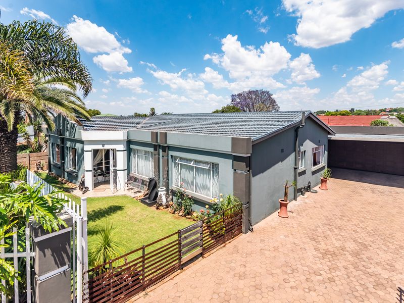 A well-maintained single-story residential property featuring a paved driveway, tiled roof, and a landscaped front garden area.