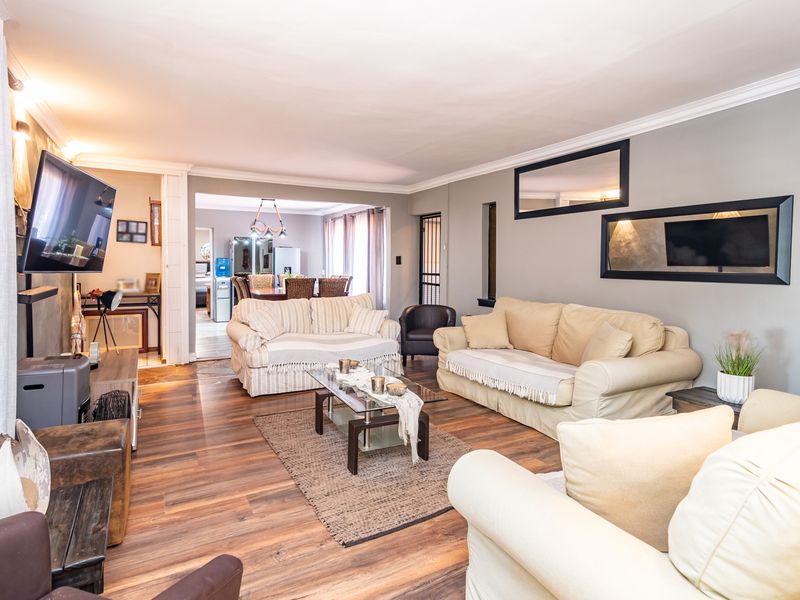 Spacious open-plan living area featuring laminate flooring, crown molding, and a seamless flow into the adjacent dining space.