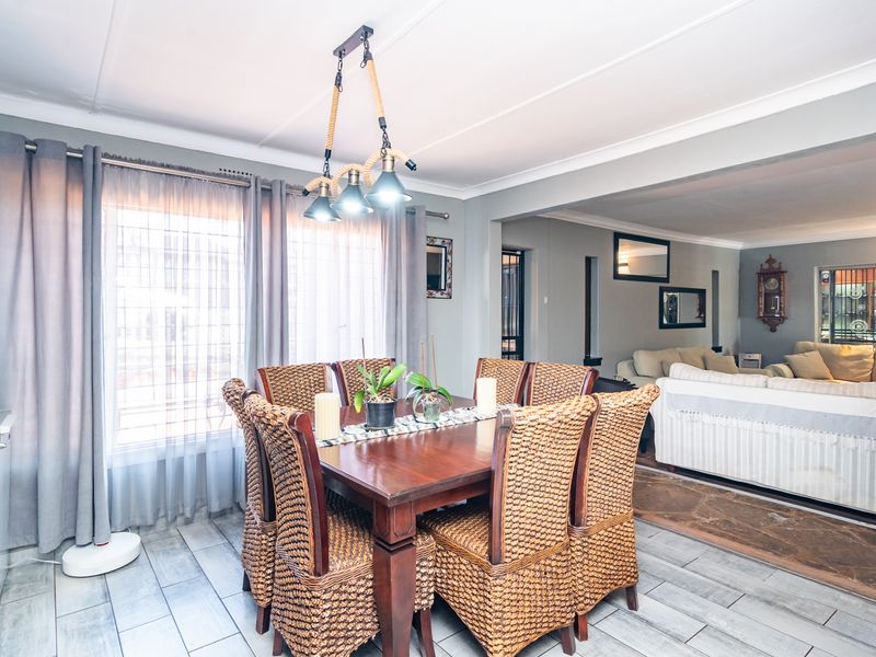 An open-plan dining and living area featuring tiled flooring, neutral wall tones, and modern pendant lighting, creating a cohesive and inviting space.