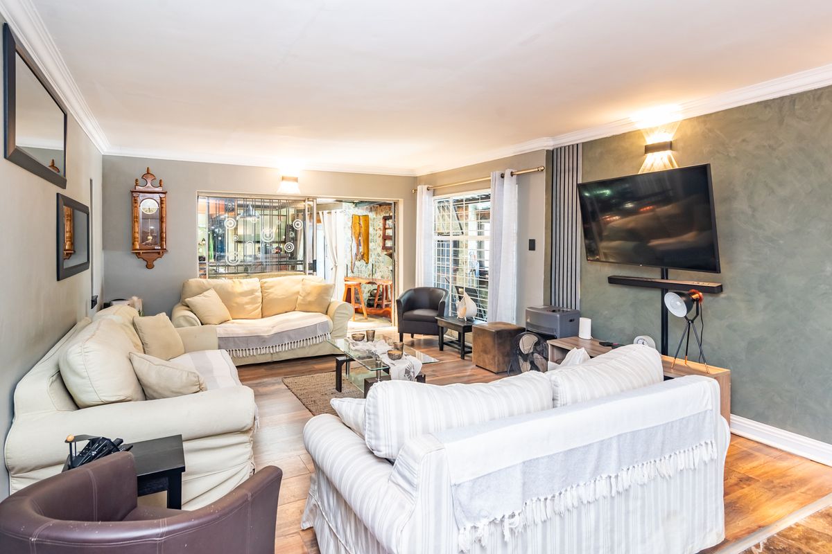 A spacious living room featuring laminate flooring, a textured feature wall, and sliding glass doors that provide natural light and access to the patio.