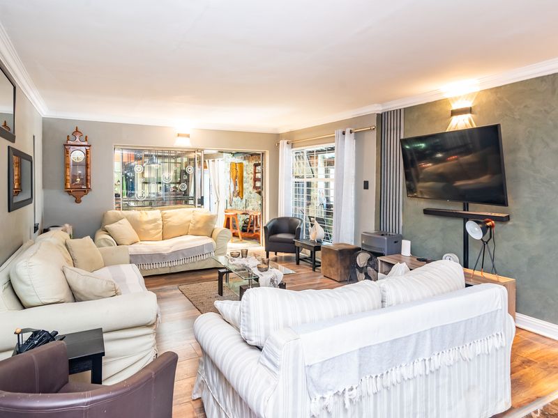 A spacious living room featuring laminate flooring, a textured feature wall, and sliding glass doors that provide natural light and access to the patio.