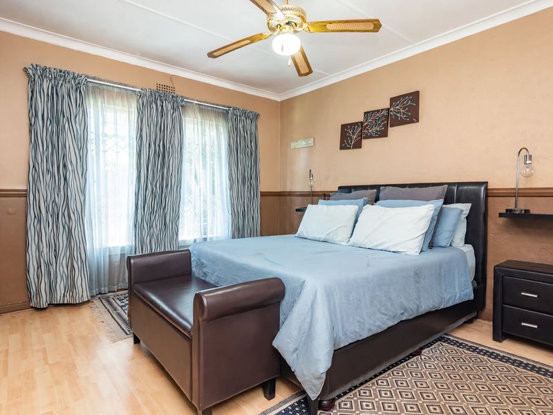 A well-maintained bedroom featuring laminate flooring, built-in cupboards, and a ceiling fan, offering a comfortable and functional living space.
