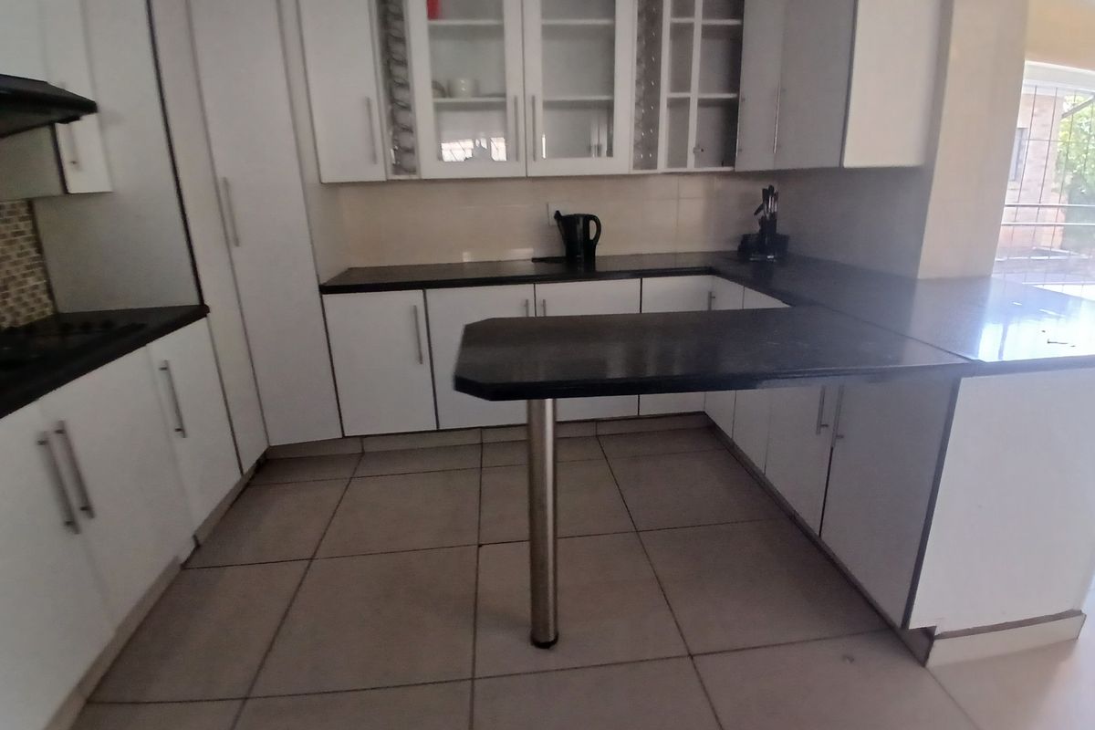 A functional kitchen featuring white cabinetry, dark granite countertops, a breakfast bar, and tiled flooring, offering a clean and practical workspace.