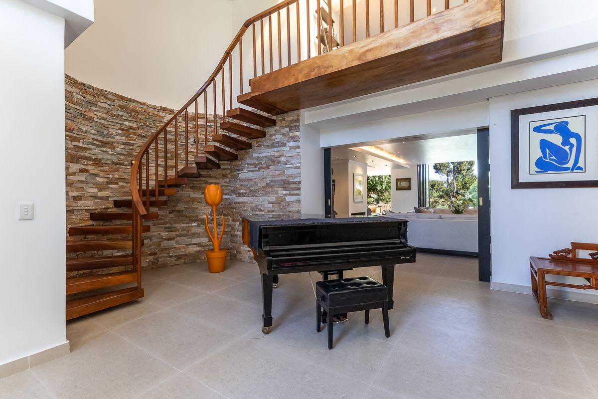 Spacious living area featuring a striking wooden spiral staircase, stone feature wall, and large sliding doors leading to an adjacent room.