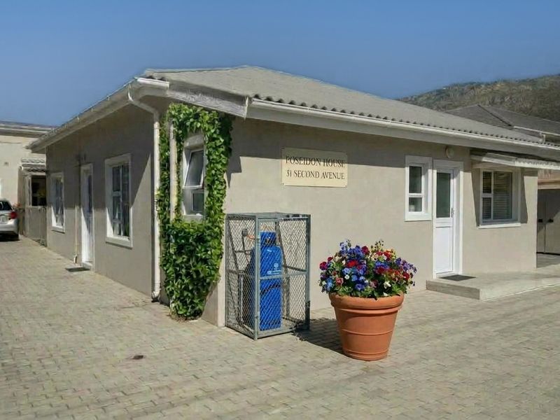 Exterior view of the front facade of Poseidon House, featuring paved driveway access, secure gas storage, and well-maintained building finishes.