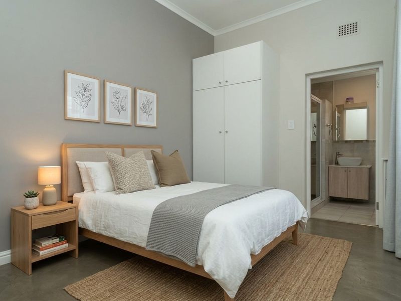 A well-presented bedroom featuring polished concrete floors, a built-in wardrobe, and direct access to an en-suite bathroom.
