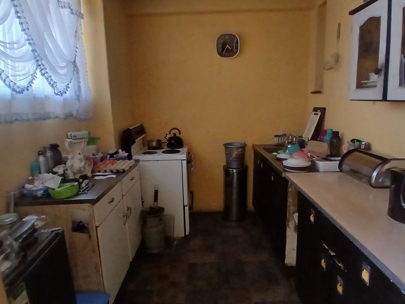 A functional kitchen featuring built-in cabinetry, laminate countertops, a freestanding stove, and a double sink, offering potential for modernization and layout optimization.