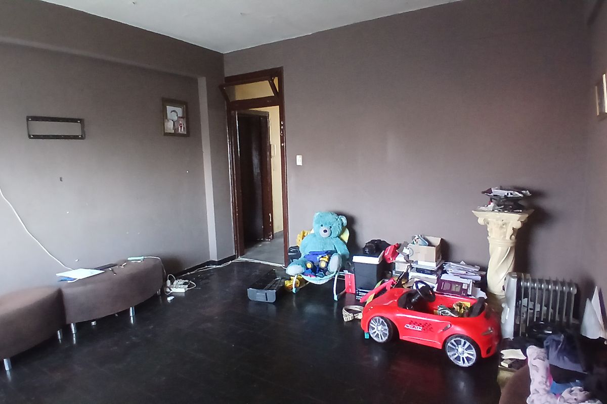A living room space featuring dark wood flooring and dark painted walls, requiring cosmetic updates to improve the overall aesthetic and appeal.