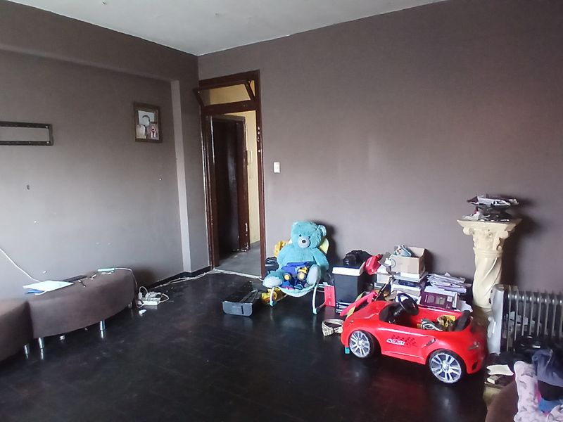 A living room space featuring dark wood flooring and dark painted walls, requiring cosmetic updates to improve the overall aesthetic and appeal.