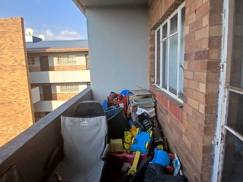 A compact balcony area featuring exposed brickwork and a sliding window, offering an outdoor space for the townhouse.