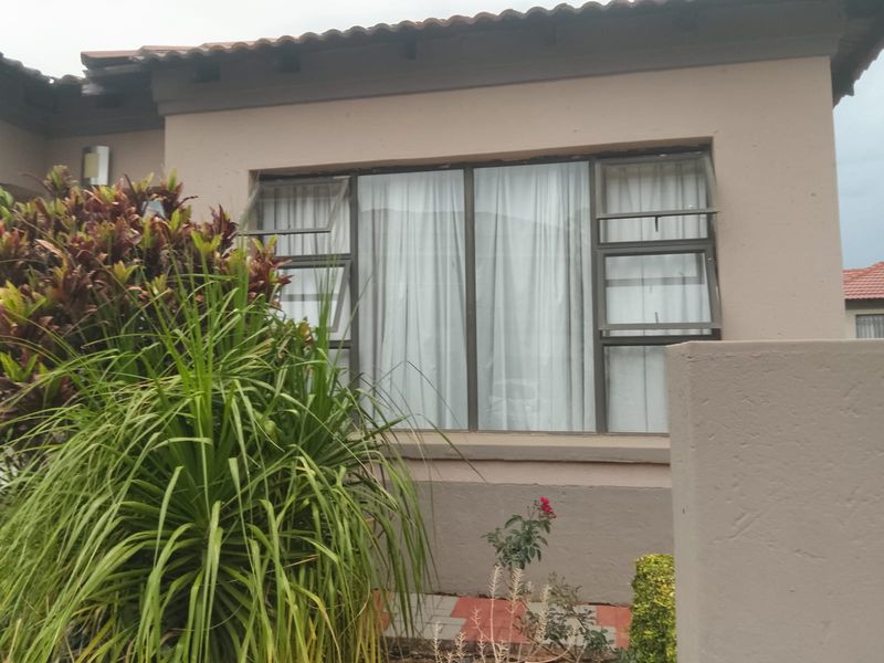 A view of the front exterior facade featuring plastered walls, a tiled roof, and aluminium-framed top-hung windows.