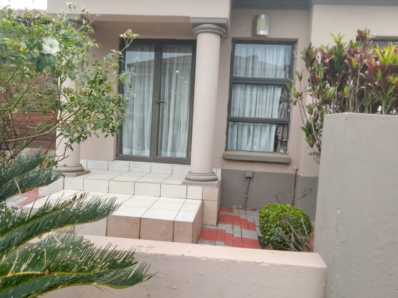 Front entrance area featuring tiled steps, decorative columns, and aluminium framed glass doors leading into the home.