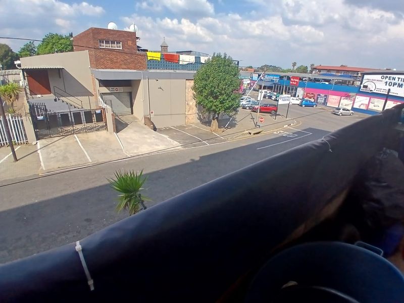 An elevated view overlooking a local street, nearby commercial buildings, and parking areas from an upper-level vantage point.