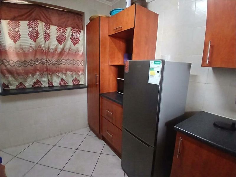 A functional kitchen featuring laminate cabinetry, dark countertops, and tiled flooring, offering a practical layout for daily meal preparation.