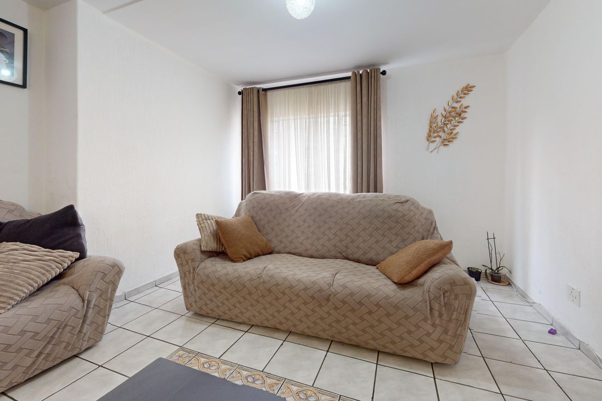 A living room featuring ceramic floor tiles and neutral wall finishes, providing a functional and well-lit space for relaxation.