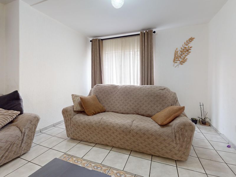 A living room featuring ceramic floor tiles and neutral wall finishes, providing a functional and well-lit space for relaxation.