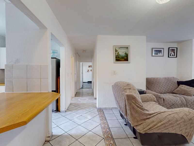 Open plan living area featuring tiled flooring, a breakfast bar, and direct access to the kitchen and internal hallway.