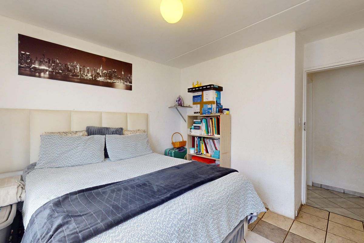 A functional bedroom featuring tiled flooring and a neutral layout, providing a comfortable space for rest.