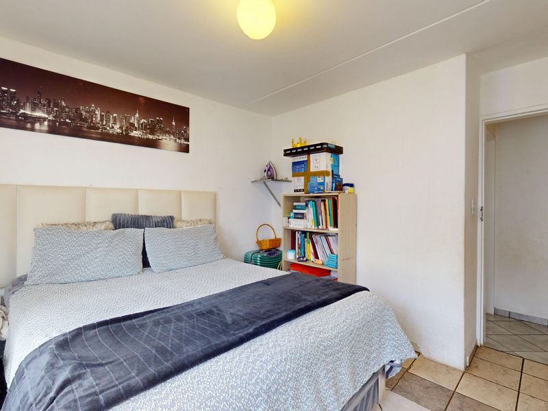 A functional bedroom featuring tiled flooring and a neutral layout, providing a comfortable space for rest.