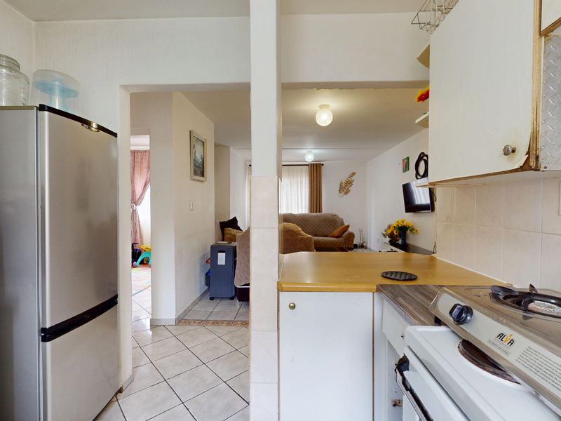 Open plan kitchen area featuring tiled flooring, built-in cabinetry, and a gas stove, flowing into the adjacent living space.