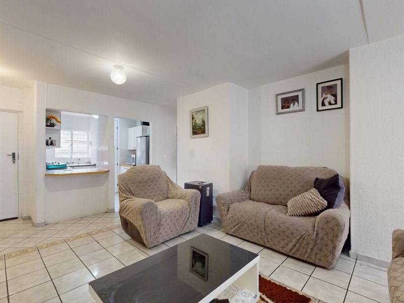 Open plan living area featuring ceramic tiled flooring and a convenient kitchen pass-through window, creating a functional and connected living space.