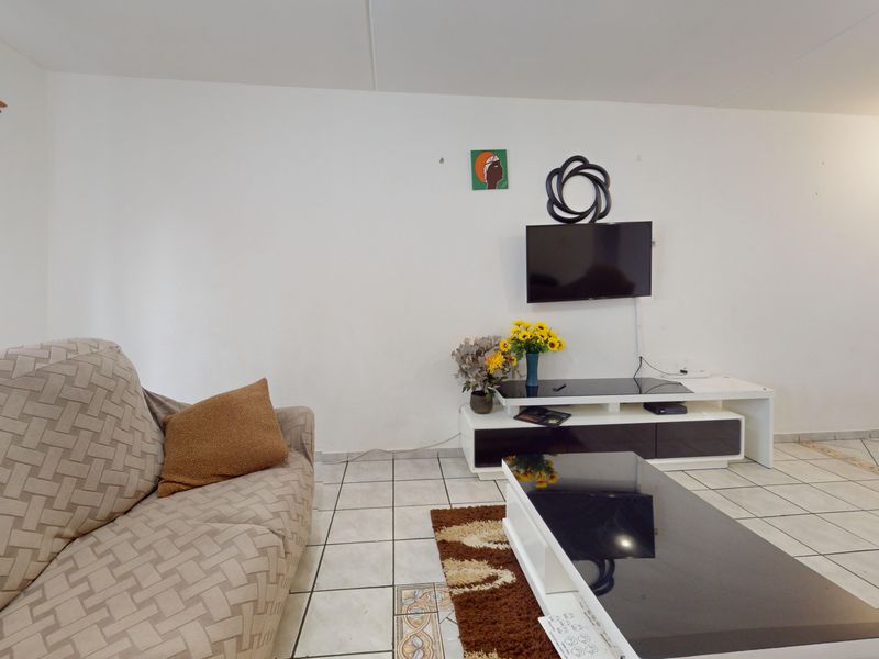 A living room area featuring tiled flooring and a neutral wall finish, providing a functional space for relaxation.