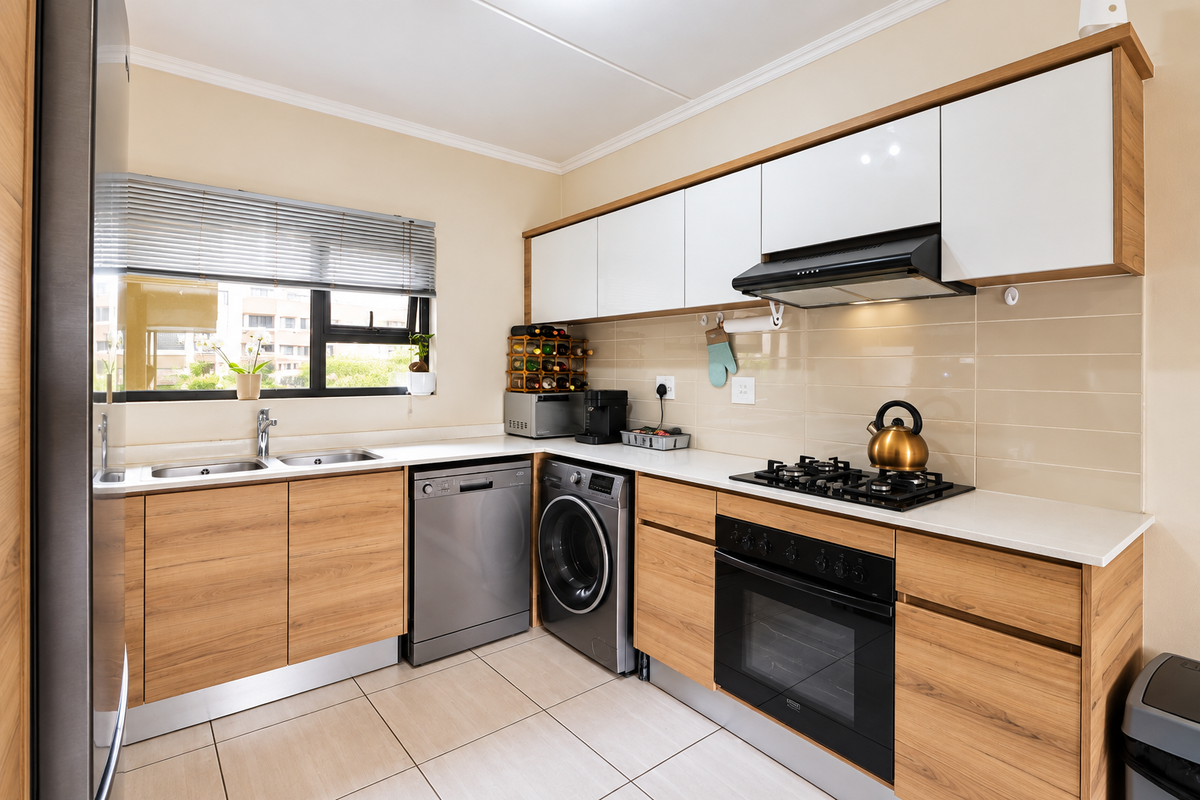 Modern kitchen featuring wood-grain cabinetry, white stone countertops, integrated gas hob, built-in oven, extractor fan, and tiled flooring with ample natural light.