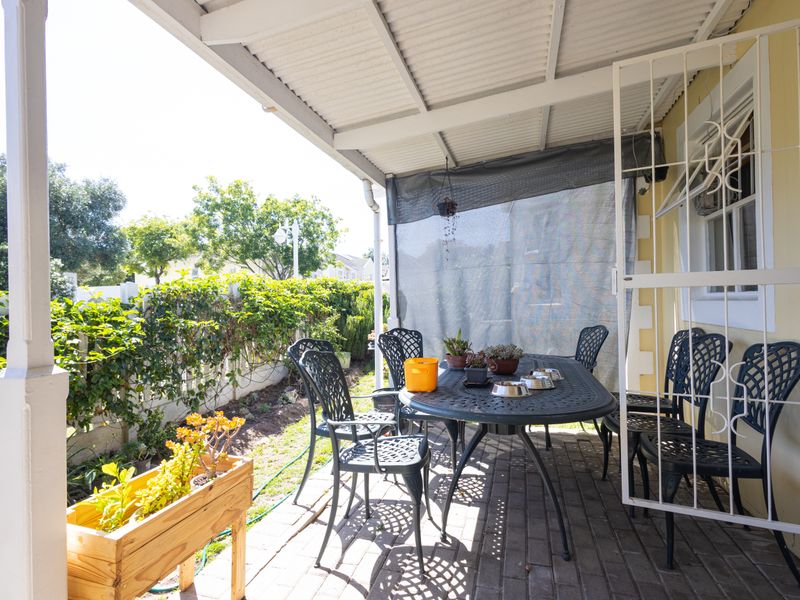 A covered outdoor patio area featuring paved flooring and a security gate, providing a functional space for outdoor dining and relaxation.