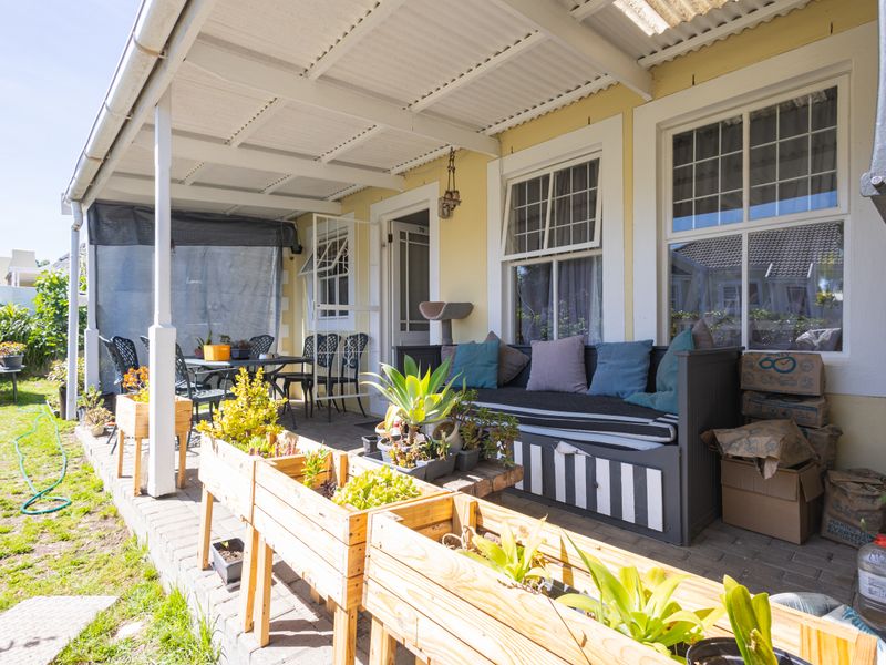 A covered outdoor patio area featuring paved flooring, timber support posts, and direct access to the home through sash windows and a door.