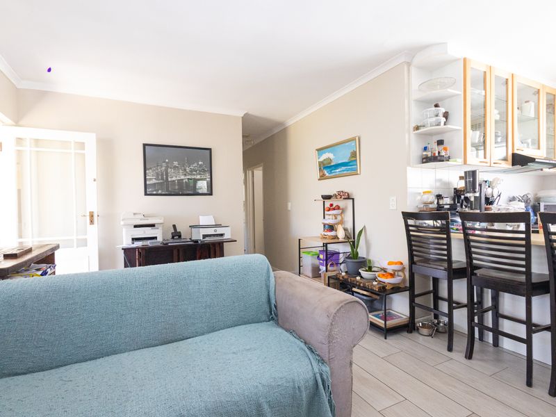 Open plan living area featuring tiled flooring and a functional kitchen with built-in cabinetry and an extractor fan.