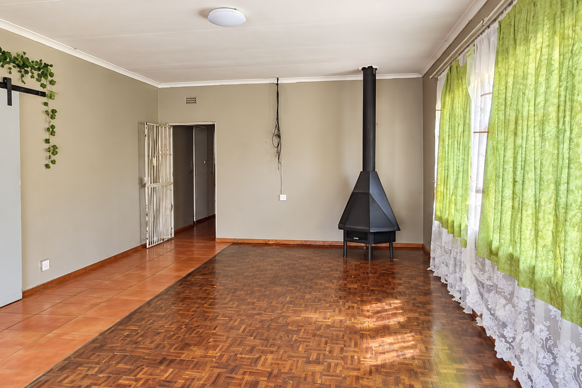 Spacious living room featuring parquet flooring, a freestanding fireplace, and a sliding barn door, offering a versatile layout for comfortable family living.