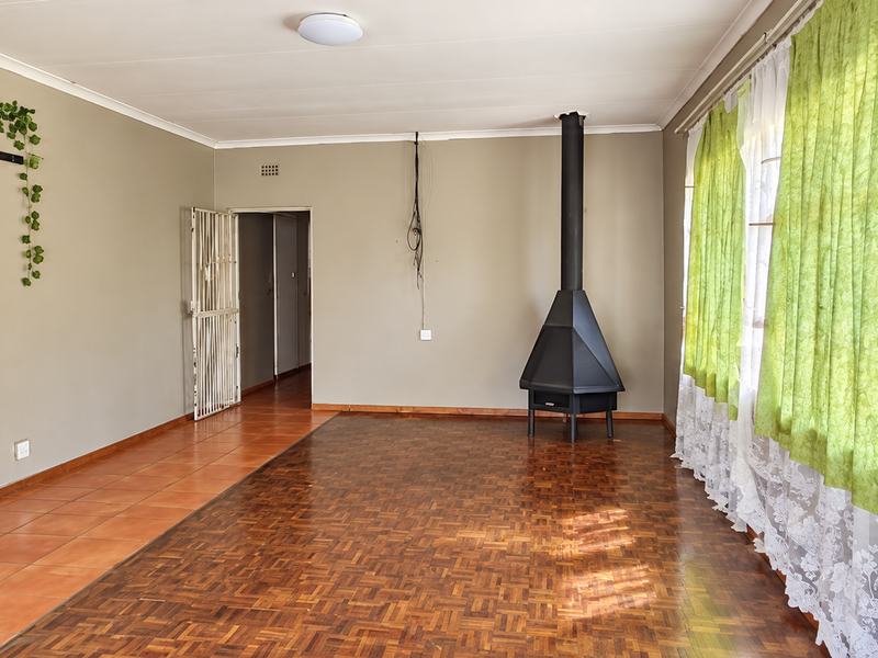Spacious living room featuring parquet flooring, a freestanding fireplace, and a sliding barn door, offering a versatile layout for comfortable family living.
