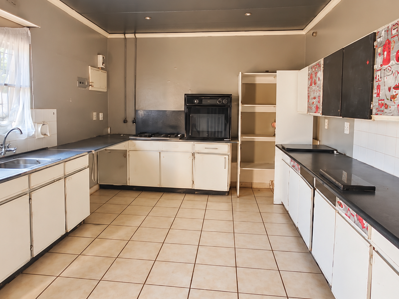 Spacious kitchen featuring extensive built-in cabinetry, laminate countertops, a built-in oven, and gas hob, finished with tiled flooring and a tiled backsplash.