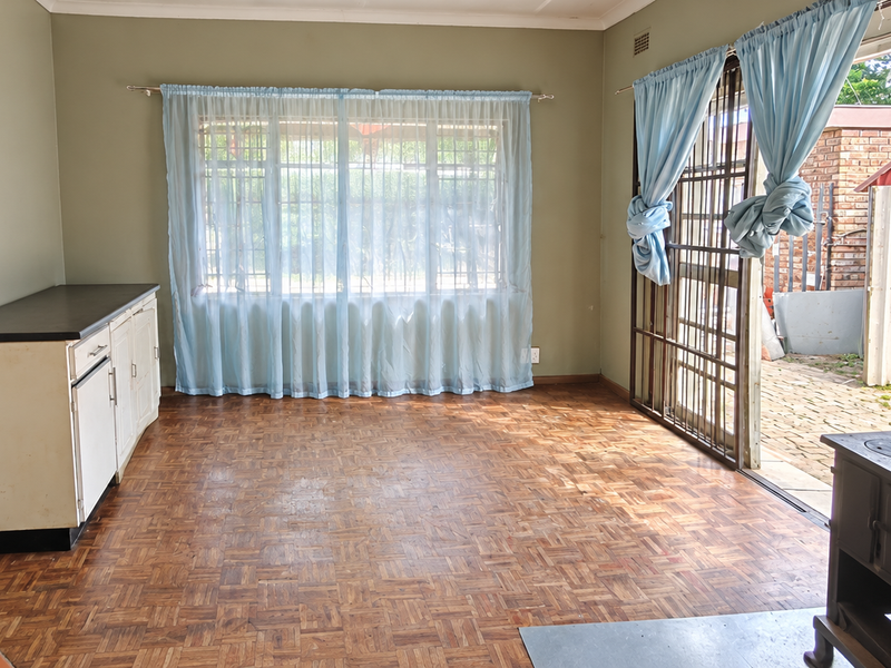 Spacious living area featuring original parquet flooring, a built-in cast iron fireplace, and direct access to the rear patio through a sliding security door.