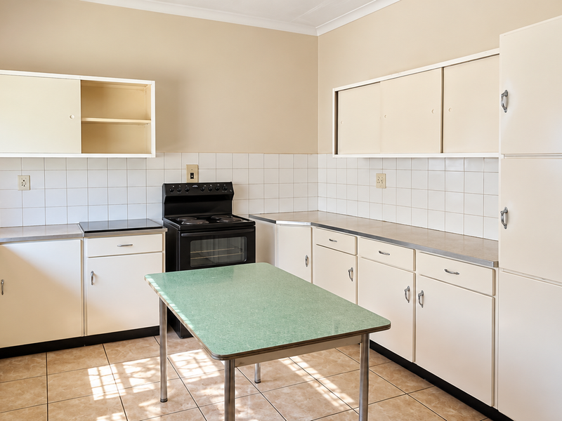 A functional kitchen featuring original built-in cabinetry, tiled backsplash, stainless steel sink, and a freestanding electric stove with tiled flooring throughout.