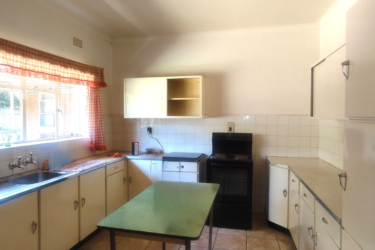 A functional kitchen featuring original cabinetry, tiled backsplash, and a freestanding stove, offering significant potential for a modern renovation.