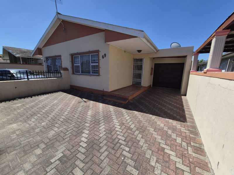 Front exterior view of a townhouse featuring a paved driveway, single garage, and secure entrance with burglar bars and security gate.