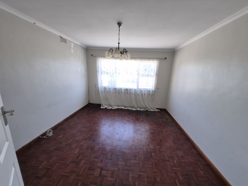 An empty bedroom featuring original parquet flooring, cove cornicing, and a central ceiling light fixture, ready for renovation or staging.