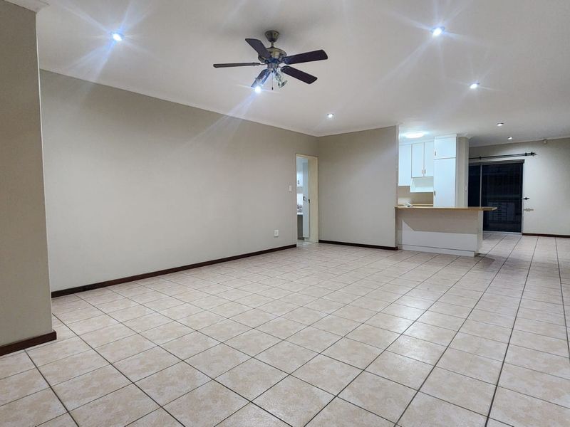 Spacious open-plan living area featuring tiled flooring, recessed lighting, a ceiling fan, and a functional kitchen with a breakfast bar.