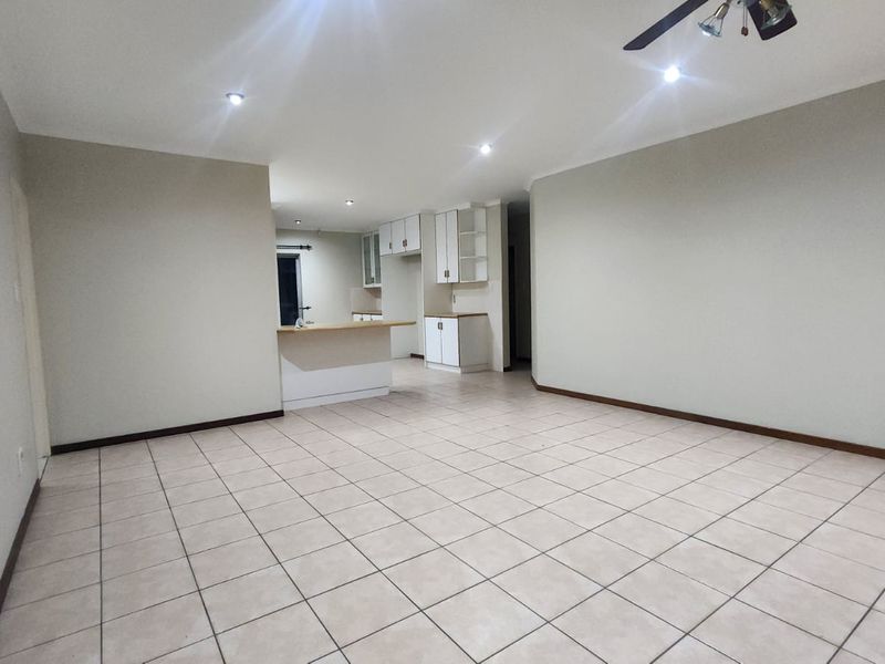 Spacious open-plan living area featuring tiled flooring, recessed lighting, and a functional kitchen with built-in cabinetry and a breakfast bar.