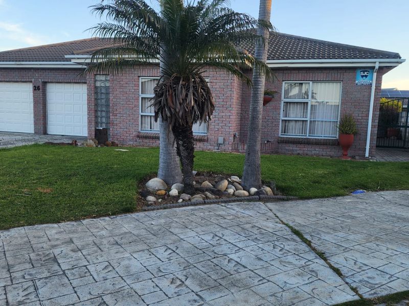 Front elevation of a single-story brick house featuring a double garage, paved driveway, and established garden area.