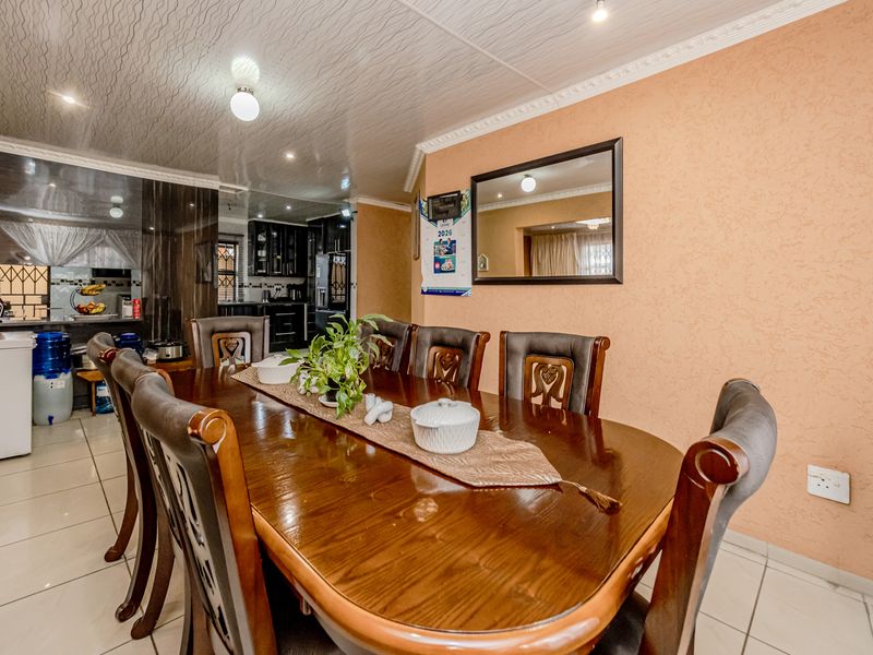 Open plan dining area featuring tiled floors, textured walls, and decorative ceiling molding, seamlessly flowing into a functional kitchen space.