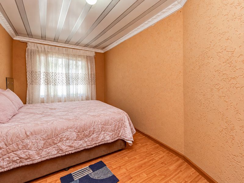 A bedroom featuring laminate flooring, textured walls, and a decorative panelled ceiling with crown molding.