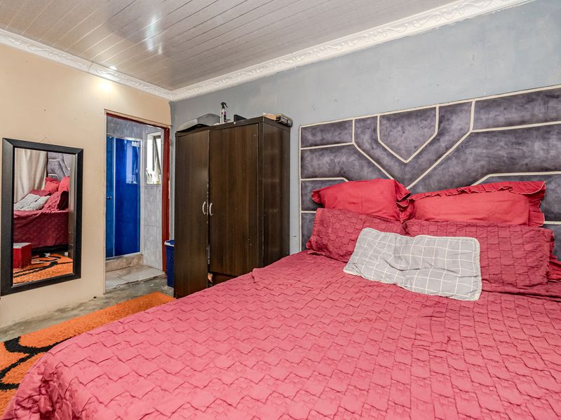 A bedroom featuring tiled flooring, decorative ceiling cornicing, and direct access to an en-suite bathroom.