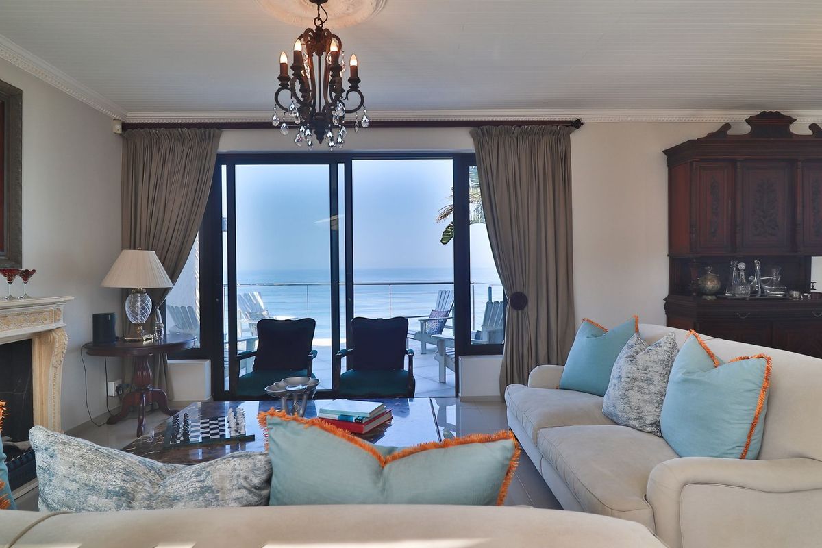 Spacious living room featuring a classic fireplace, elegant chandelier, and large sliding glass doors opening to a scenic ocean view.
